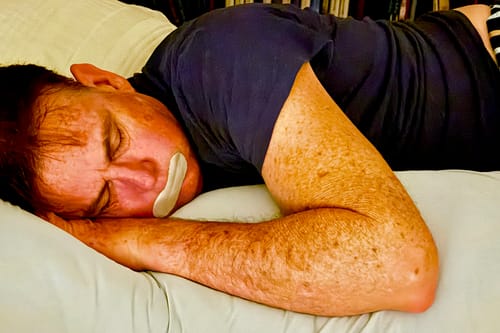 Customer's Snuggi Cooling Pillowcase on a light blue body pillow with a person sleeping comfortably on it.
