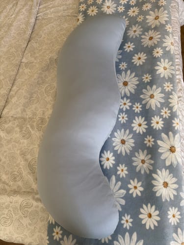 Customer's Snuggi Cooling Pillowcase, a curved light blue body pillow resting on a bed with a floral daisy blanket