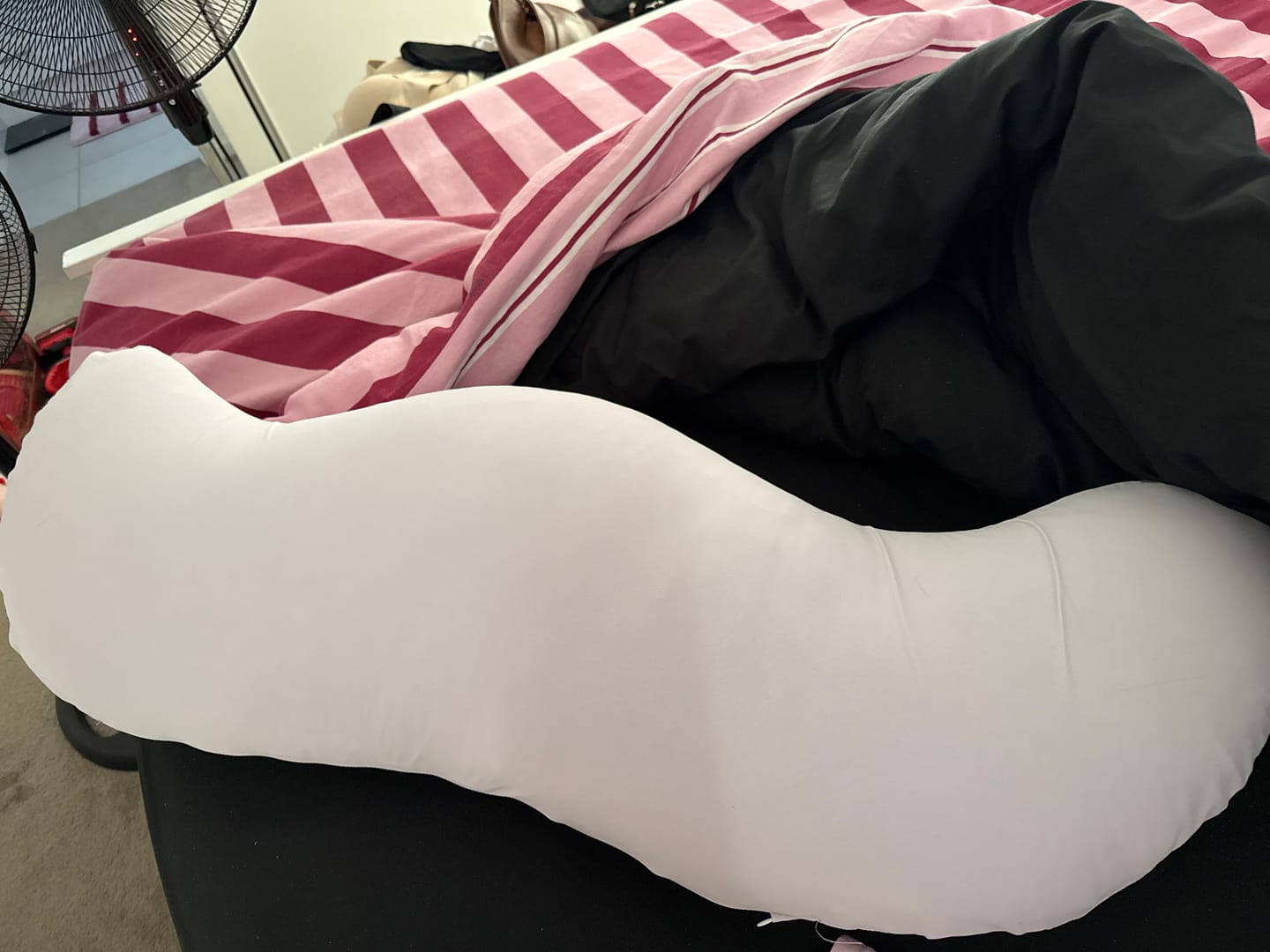 Customer's Snuggi™ Cooling Pillowcase shown in white on a bed with red and white striped bedding.