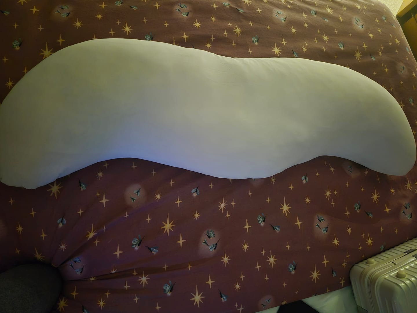 Customer's Snuggi Cooling Pillow Case, a long white pillow lying horizontally on a patterned bedspread.